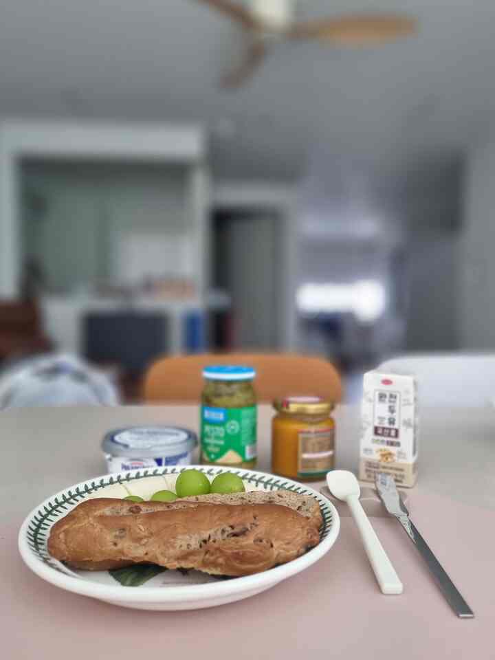 白とナチュラル色調のキッチンとダイニングテーブル、パンとジャムが置かれた雰囲気のあるおうちカフェ空間