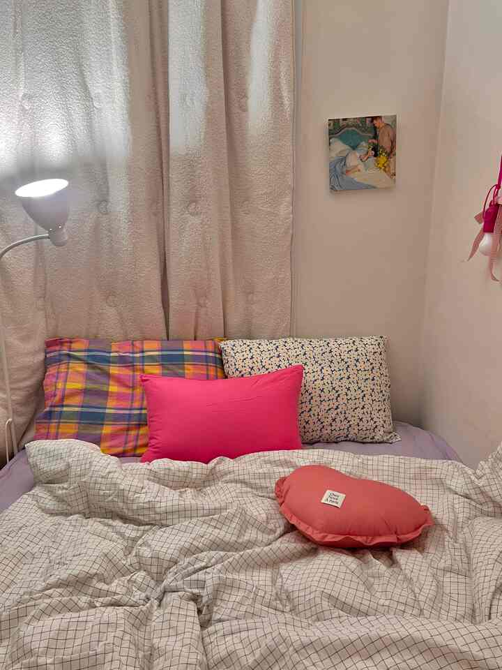Cozy bedroom in white and pink tones featuring cushions and checkered bedding with soft lighting