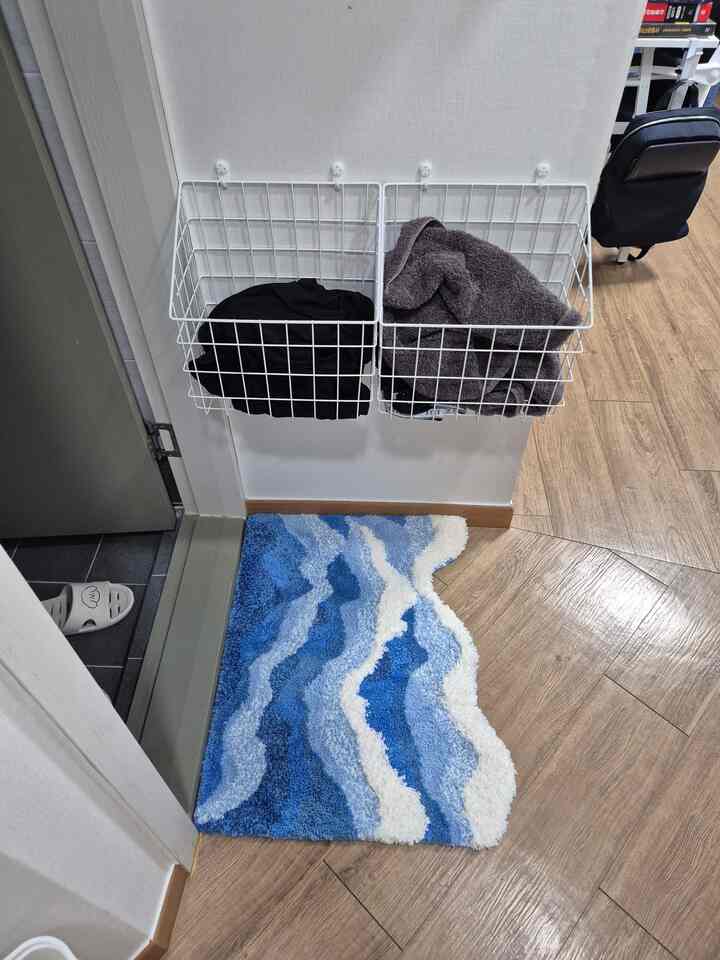 木目調の床の玄関に、青と白の波模様のバスマットが配置された清潔感のある空間