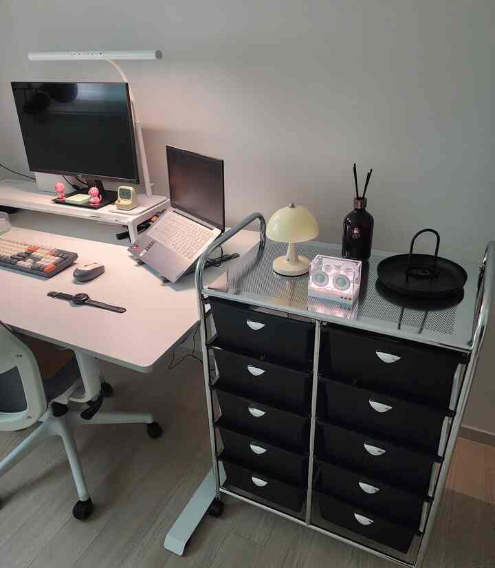 白を基調としたワークスペース、白いデスクとクロムの黒い引き出しトロリーが配置された清潔感のあるインテリア