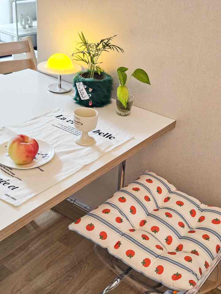 Bright white-toned kitchen featuring a mid-century style dining chair and a tomato-patterned cushion creating a cozy atmosphere