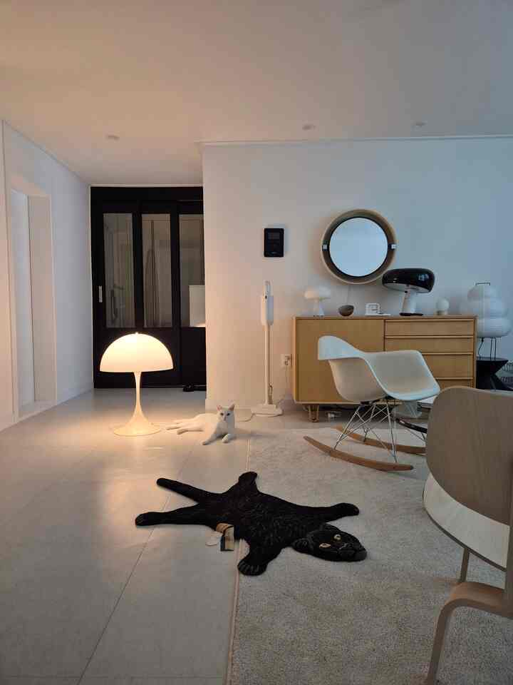 White and natural tones living room featuring sideboard, armchair, and warm lighting creating cozy atmosphere