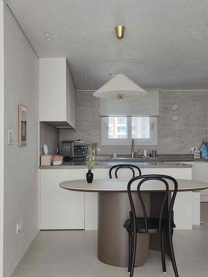 白とベージュのトーンでまとめられたモダンなキッチン、ダイニングテーブルと黒い椅子が配置された雰囲気のあるインテリア