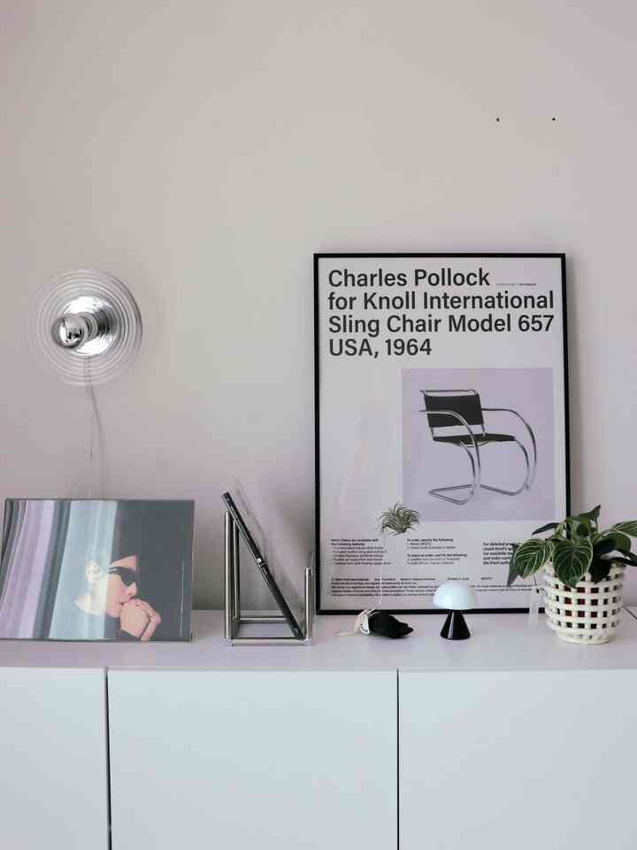 ホワイトトーンのモダンな玄関空間、白い収納の上に額縁と植物が配置されたインテリア