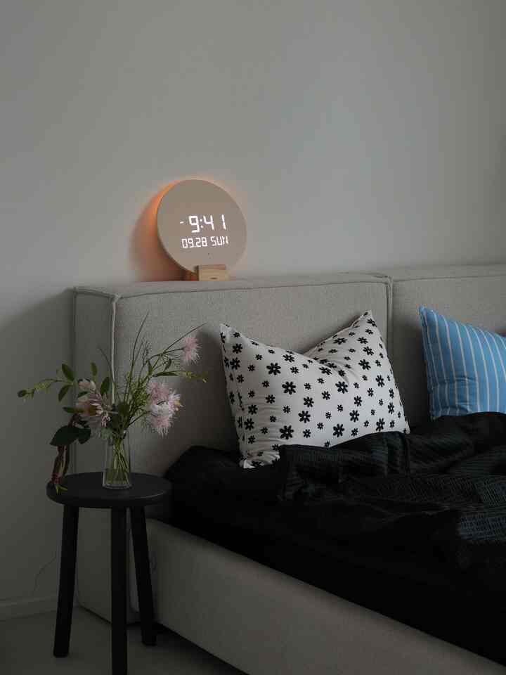 グレーと黒を基調とした寝室、ベッドと花瓶のある黒いナイトテーブルが配置された落ち着いた雰囲気のインテリア