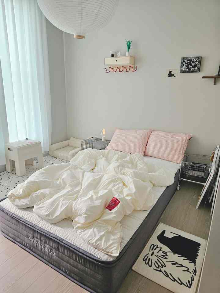 Beige and white toned bedroom with large mattress, white bedding, and pink pillows creating cozy atmosphere