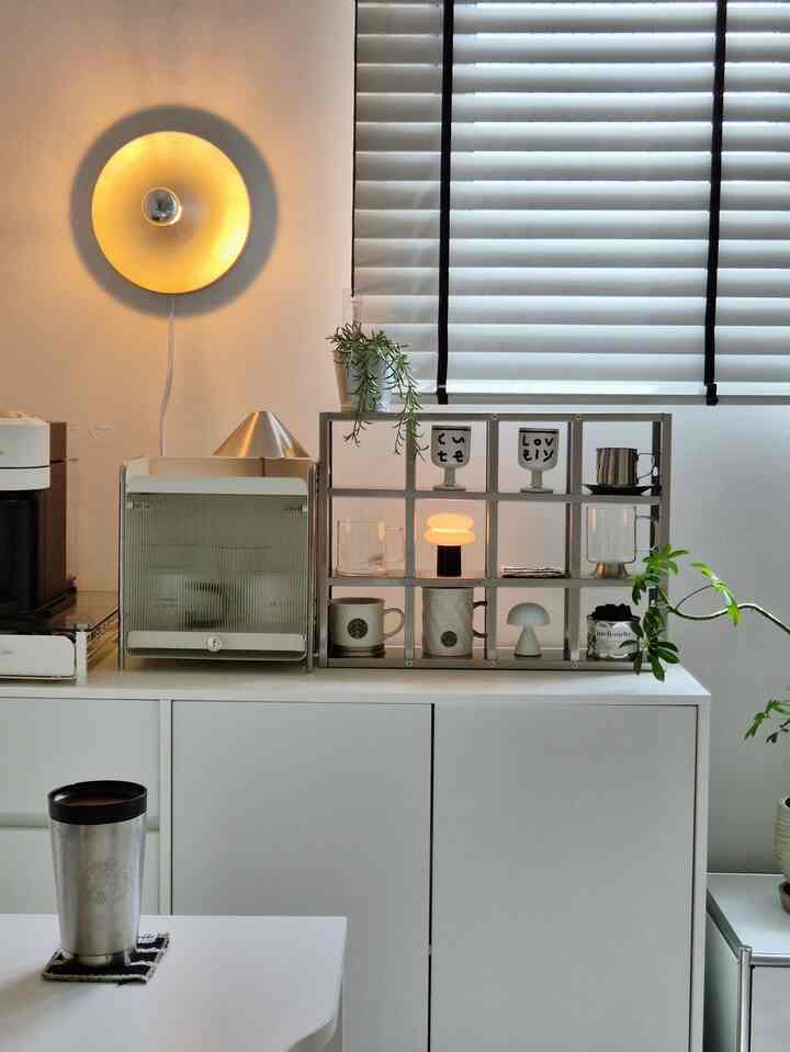 White and silver toned kitchen space featuring mid-century modern lighting and home cafe items, with a clean and calm atmosphere