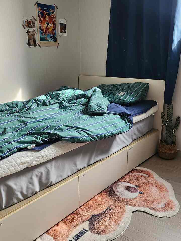 ナチュラルなベージュ色調の子供部屋、収納ベッドと緑のストライプ柄の寝具、かわいいクマの形のラグが配置された雰囲気のあるインテリア