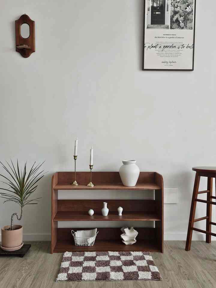 ナチュラルな色調のリビング、木製家具と植物、キャンドル、ラグが配置されたシンプルで雰囲気のあるインテリア