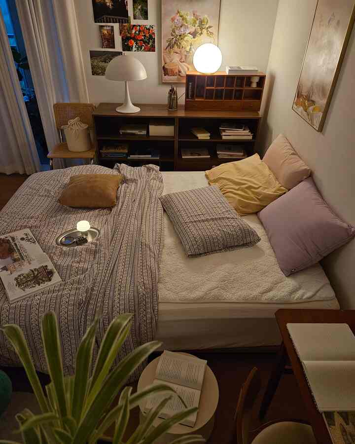 ホワイトとブラウンの色調の6畳の寝室、書棚とテーブルランプが配置された居心地の良いワンルーム空間