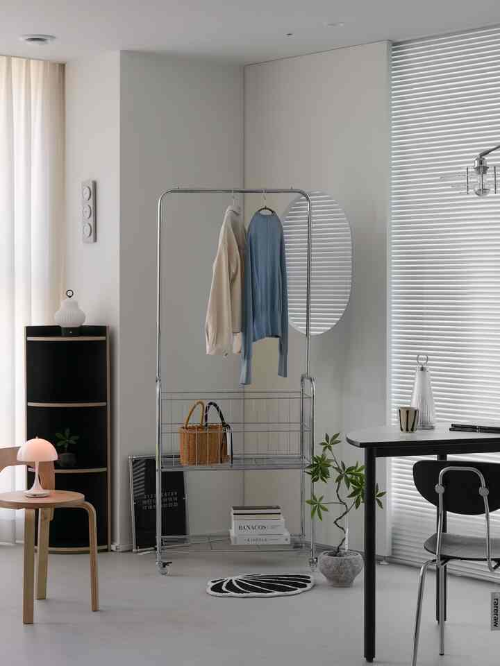 ホワイトとグレーのトーンのリビング、中央に収納可能なメタルラックとミニマルな照明が配置された洗練されたインテリア