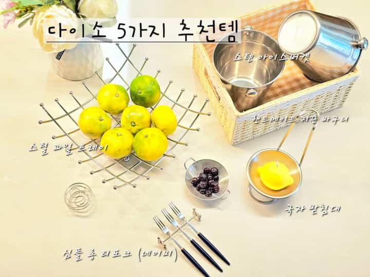 明るく柔らかなベージュ調のキッチンスペース、ステンレス製のフルーツトレイとアイスバケツ、ネイビーのロングティーフォークがシンプルで整然と配置された印象的なテーブルインテリア