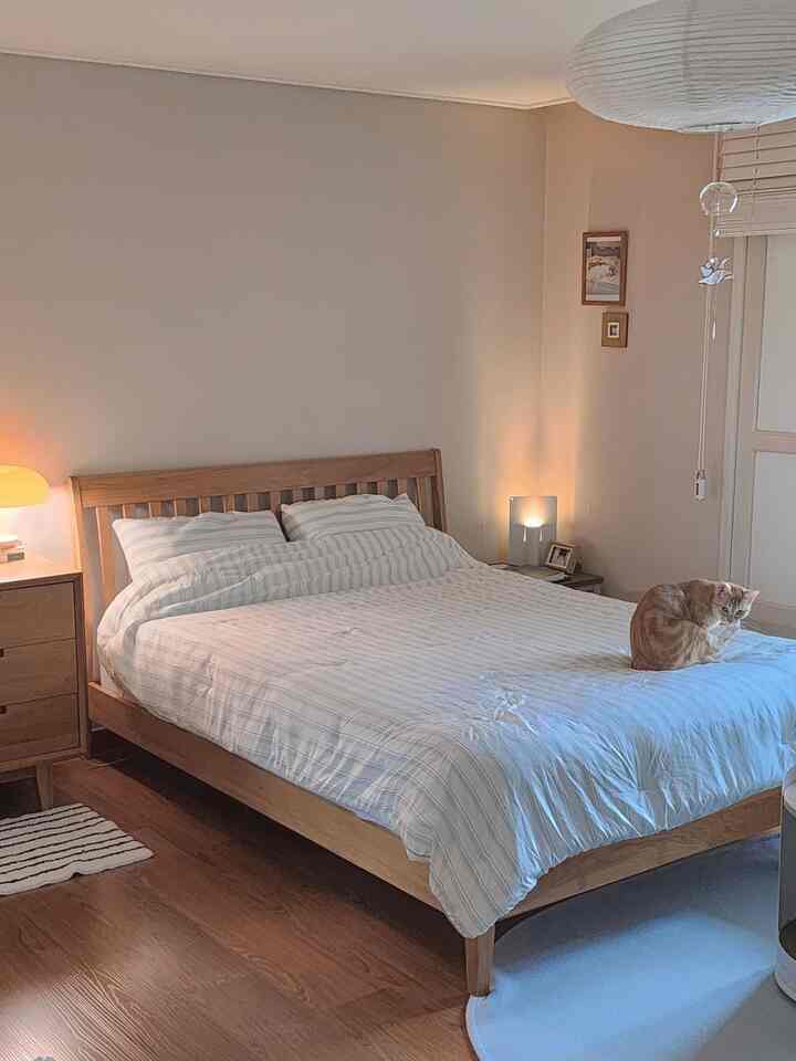 ナチュラルなブラウン調の寝室、ミッドセンチュリーモダンのベッドと猫がいる落ち着いた空間