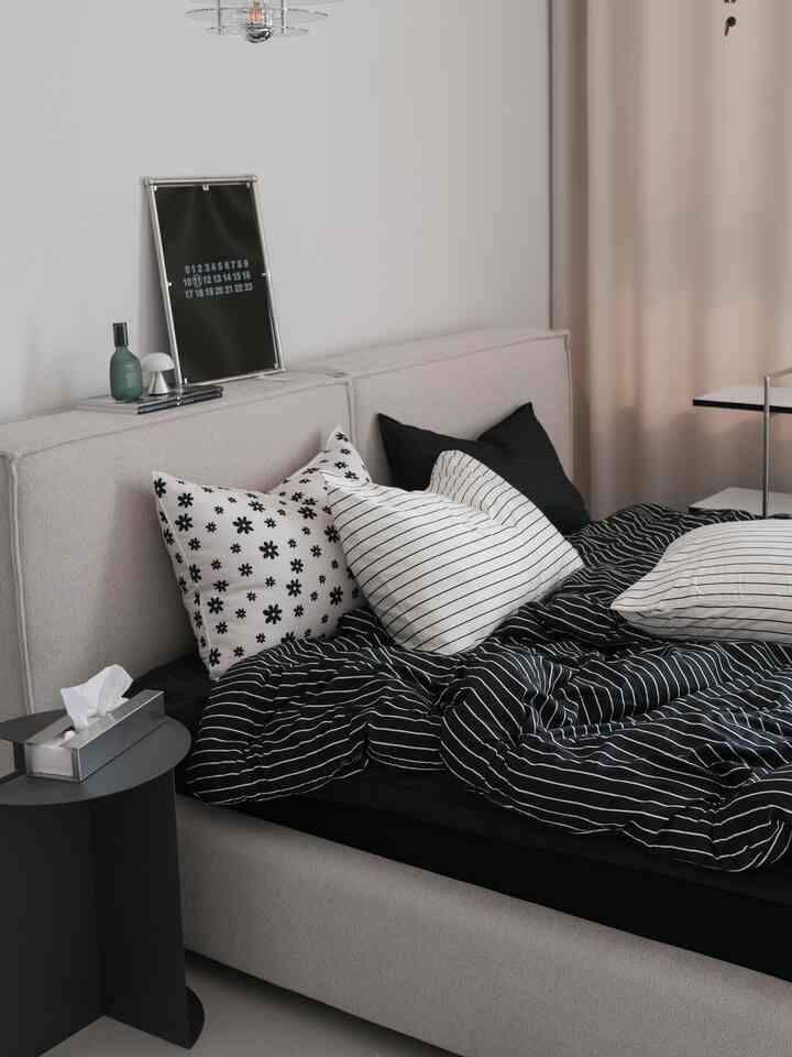 モダンでベージュと黒のトーンの寝室、ベージュのベッドと黒のサイドテーブルが配置されたシンプルな空間