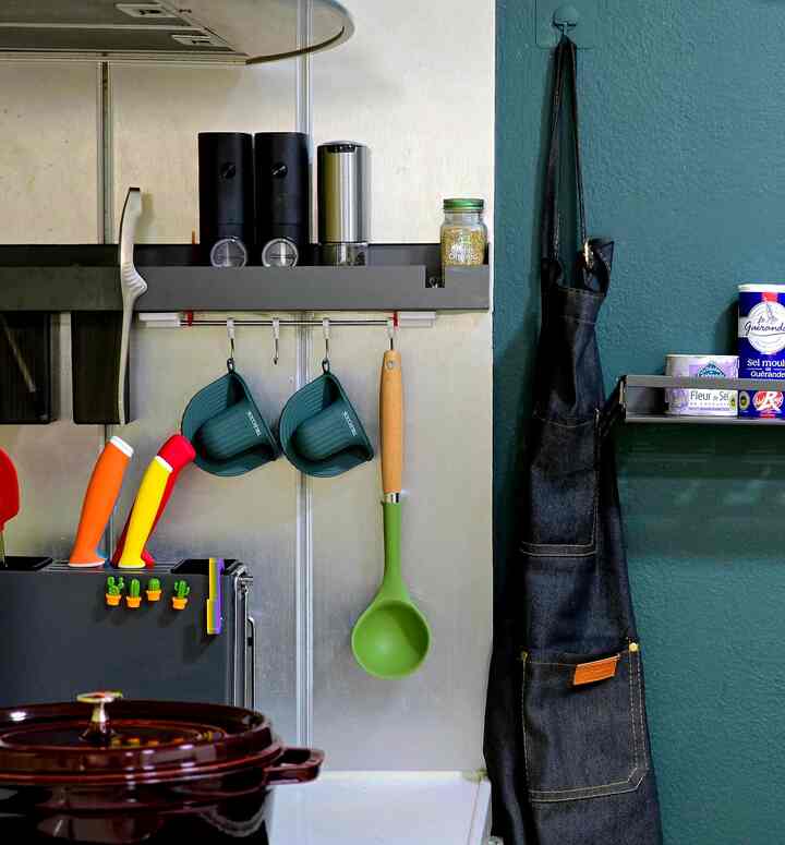 緑色の壁と黒いエプロンがあるキッチン空間、整理された調理器具が配置された清潔感のある雰囲気