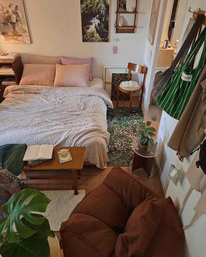 ベージュとブラウン系の寝室、広いベッド、ソファ、木製椅子、植物、花柄のラグが配置された雰囲気ある空間