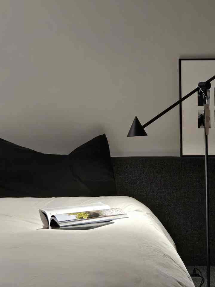 白と黒のトーンが特徴の寝室、シンプルな寝具とフロアランプが配置されたシンプルモダンなインテリア