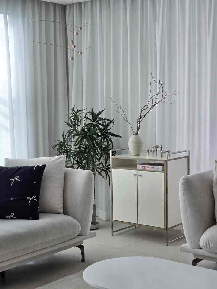 白とナチュラルカラーのリビング、ミッドセンチュリーモダンの収納キャビネットとソファ、植物が配置された雰囲気のあるインテリア