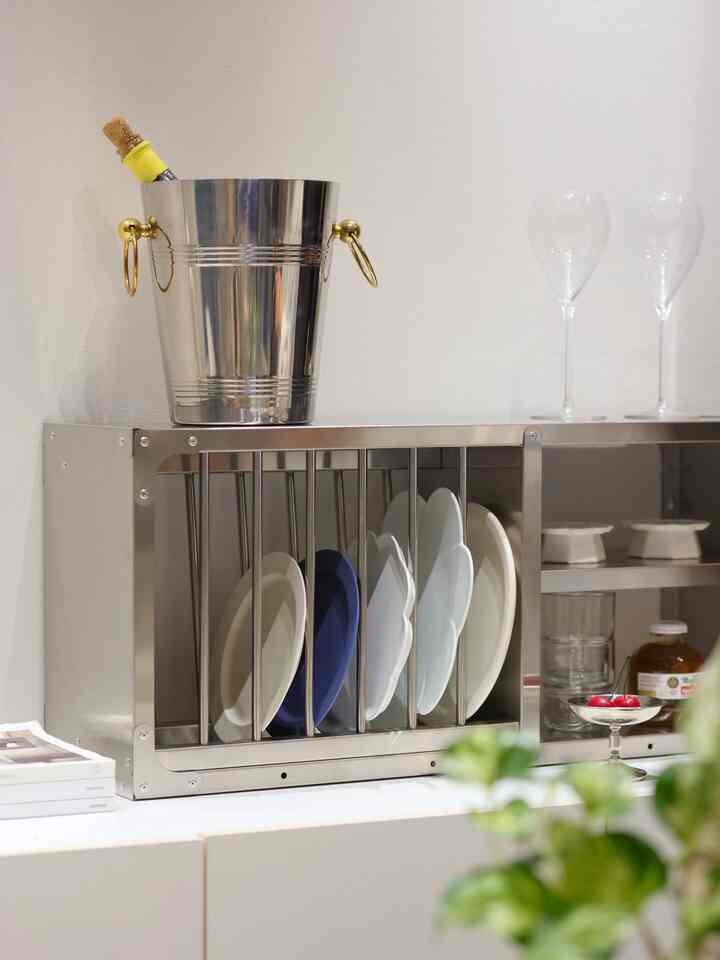 ステンレス製のキッチン収納棚の上にワイングラスとアイスペールが置かれた、清潔感のあるコンパクトなキッチンスペース