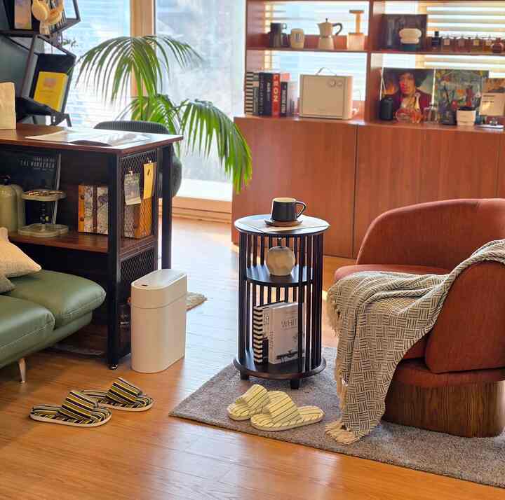 温かみのあるナチュラルカラーのリビング、ソファやサイドテーブル、ブランケットと室内履きが配置された雰囲気のあるインテリア