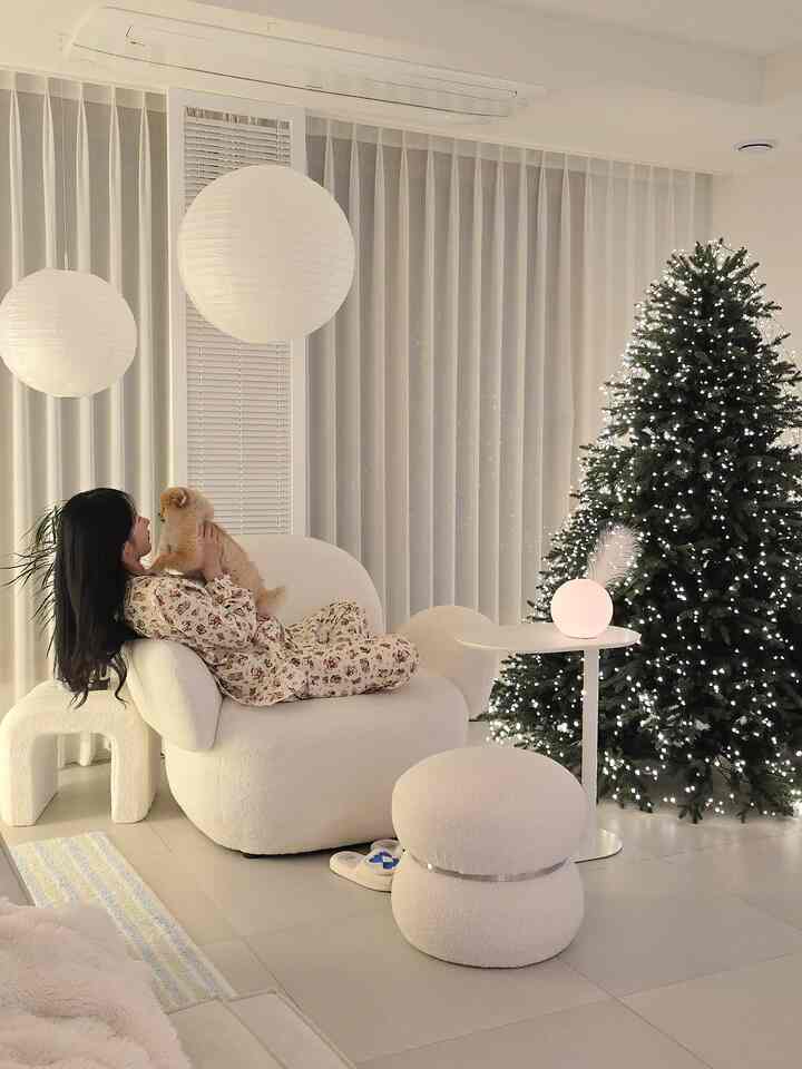 ホワイトトーンのリビング、丸いアームチェアとクリスマスツリーが配置され、温かみのある雰囲気のインテリア