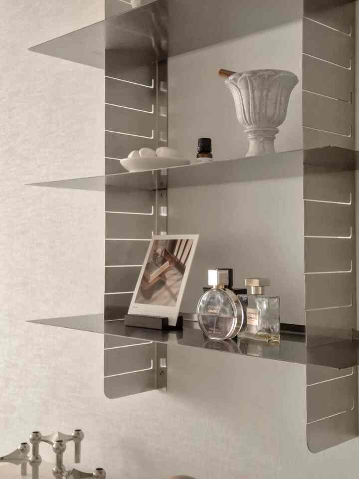 シルバートーンのステンレス鋼壁棚にミニマルなオブジェが配置された清潔感のある空間