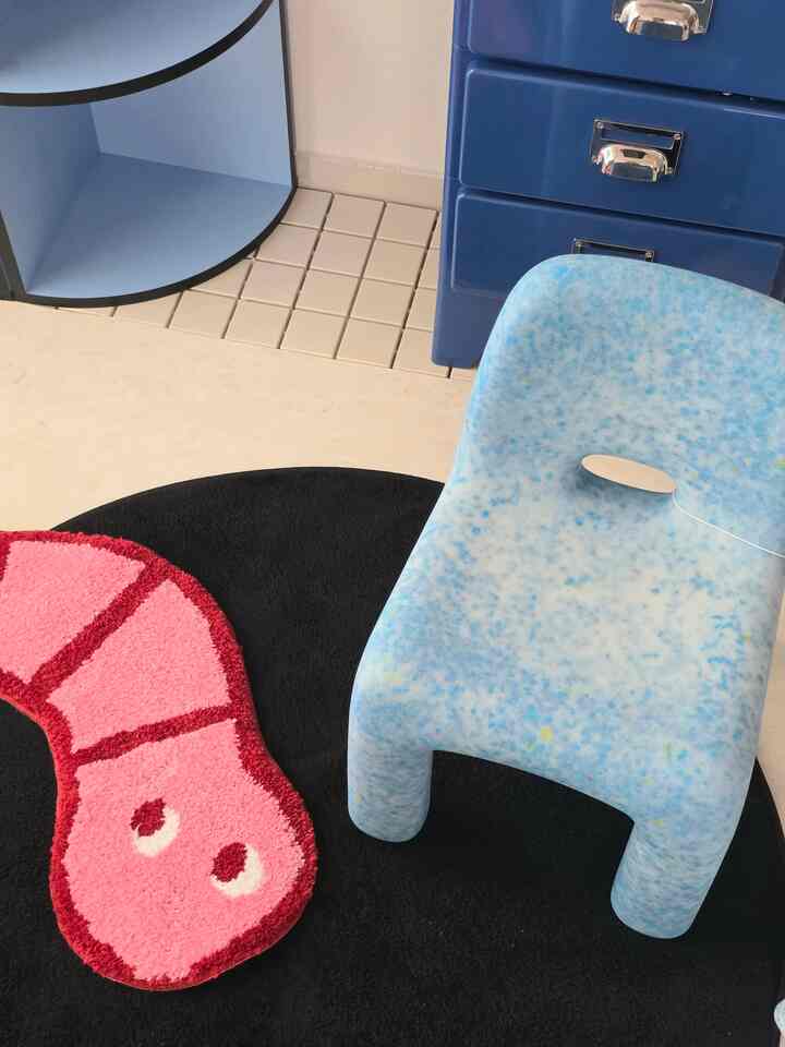 パステルブルーとブラックを基調とした子供部屋、遊び心のあるピンクのエビ型ラグとブルースツールが配置された暖かみのある空間