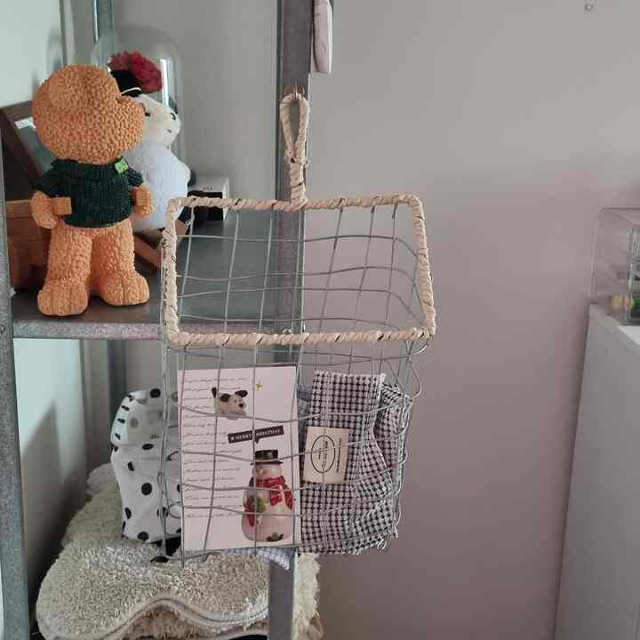 白いトーンの小さな空間、収納バスケットとペットのおもちゃが配置された実用的なインテリア