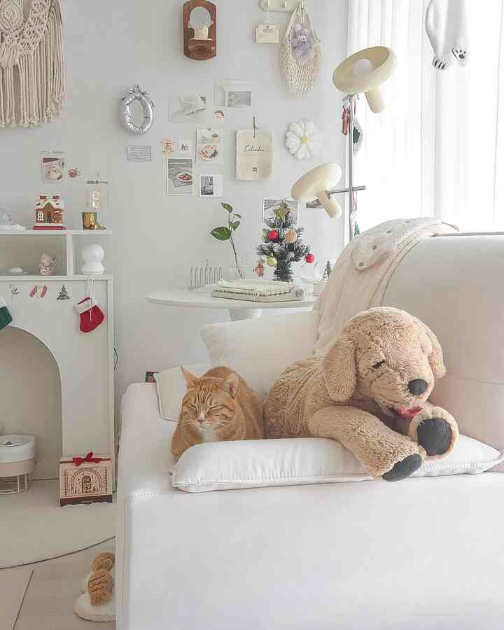 明るい白色調のリビングルーム、白いソファに猫と小さなクリスマスツリーが配置されたシンプルで自然な雰囲気のインテリア