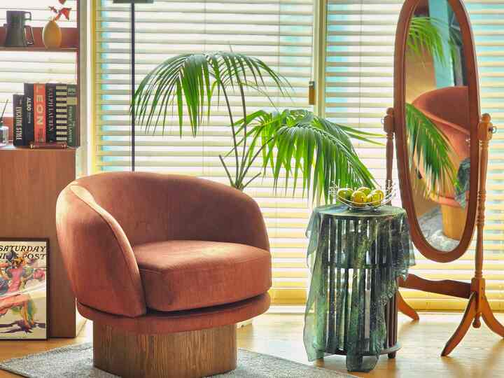 Natural-toned living room with wood tone and beige hues featuring a curved sofa, large plant, and soft lighting