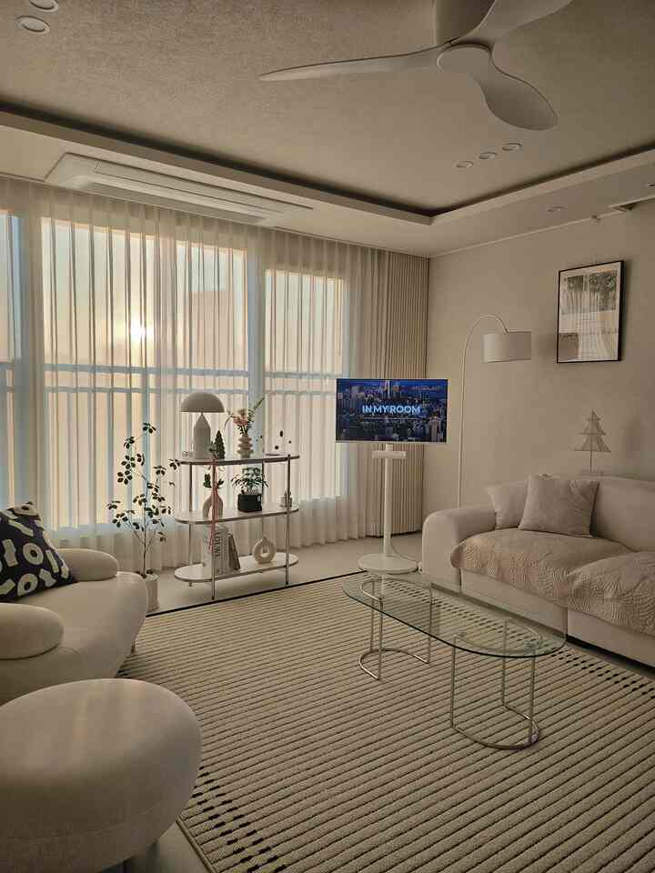 ナチュラルモダンスタイルのリビング、白いカーテンとソファが配置された落ち着いた雰囲気の空間