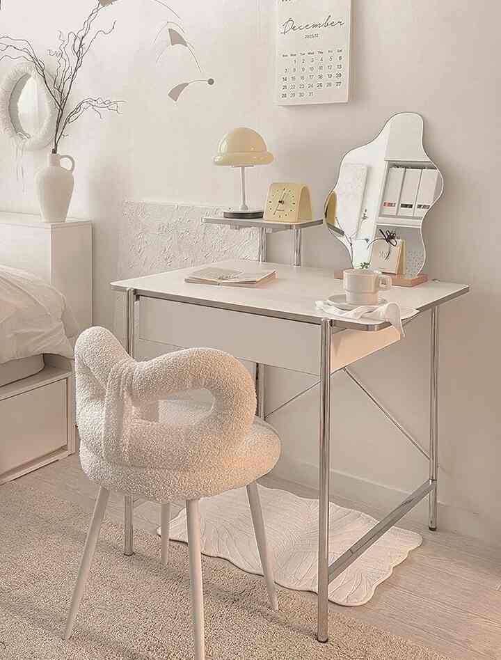 白とシルバーの色調が印象的な寝室の一角に配置された、コンパクトな化粧台とファブリックスツールの雰囲気のあるインテリア
