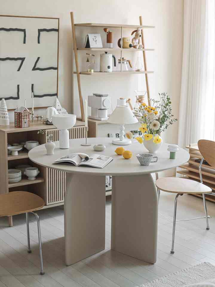 ベージュとナチュラルウッドトーンのダイニング、ラウンドテーブルと木製の椅子が配置されたシンプルで清潔感のある空間