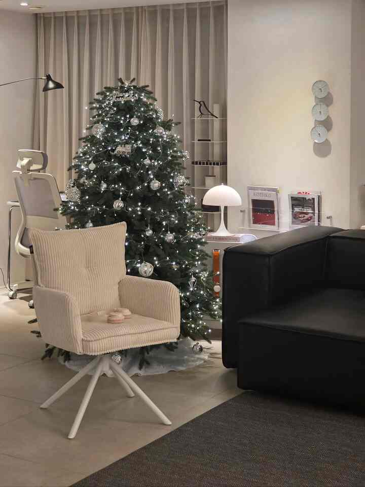 Beige and black toned living room featuring a decorated Christmas tree, armchair, and sofa with cozy atmosphere