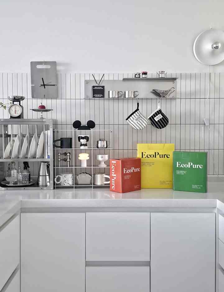 白を基調とした清潔なキッチン、ステンレス棚と整然と並べられたゴミ袋セットが配置された印象的な空間