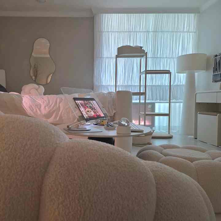 柔らかなナチュラルモダンの一人暮らし向けリビング、丸テーブルとスツール、ペットベッドと猫が配置されたシンプルな空間