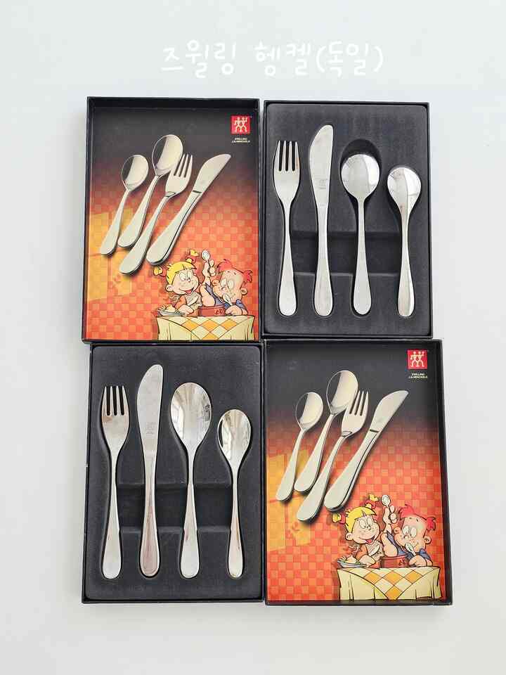 シルバーのカトラリーセットが4つの黒いトレイにきれいに配置され、赤いチェック柄のパッケージが見えるキッチン用具の写真