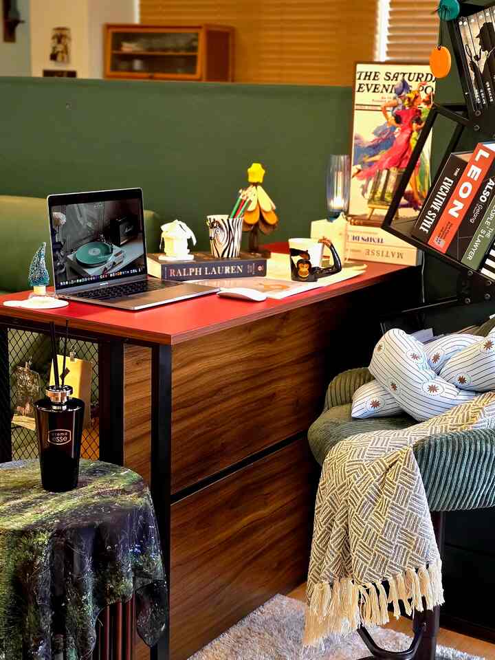 Natural color and wood tone compact home office featuring a red desk and green sofa creating cozy interior
