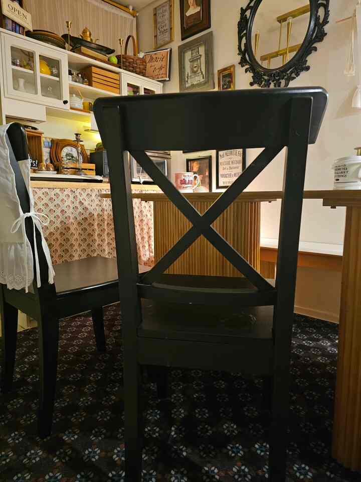 ヴィンテージ風のダイニングルーム、黒いダイニングチェアと木目調のテーブル、柄入りのカーテンが調和した印象的な空間