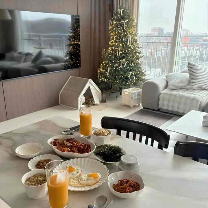 ベージュのナチュラルなリビング、大理石のテーブルに朝食とオレンジジュースが置かれた落ち着いた空間