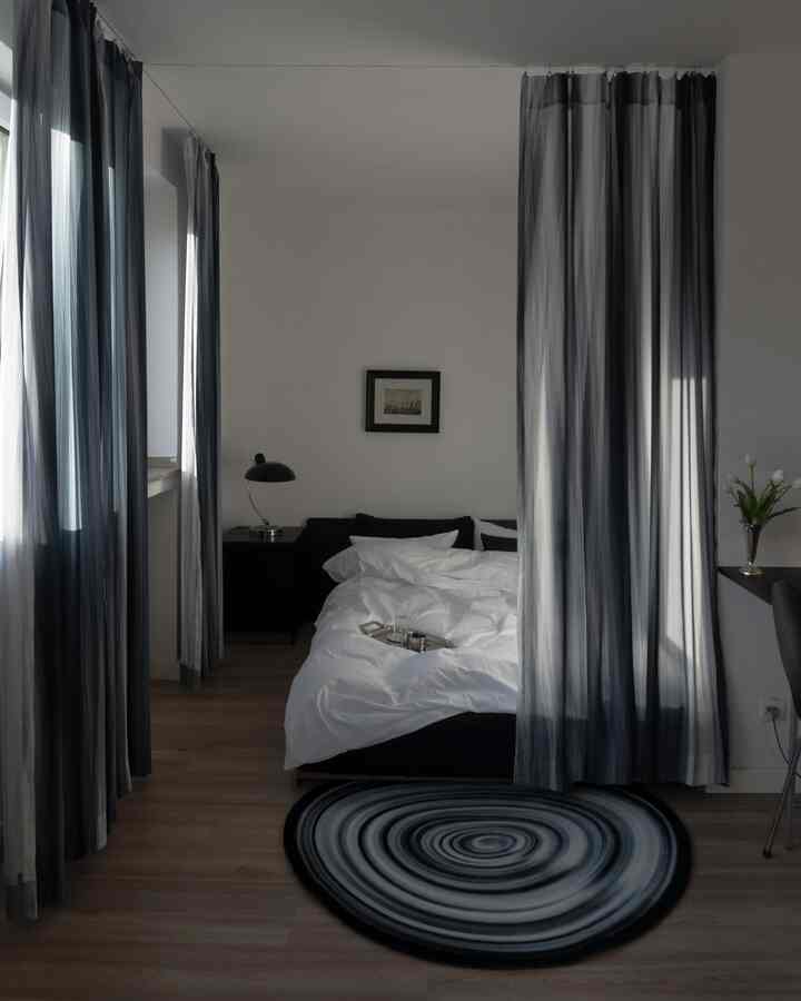 Black and white toned bedroom featuring a uniquely patterned Winter Black rug and curtains, creating a modern and calm atmosphere