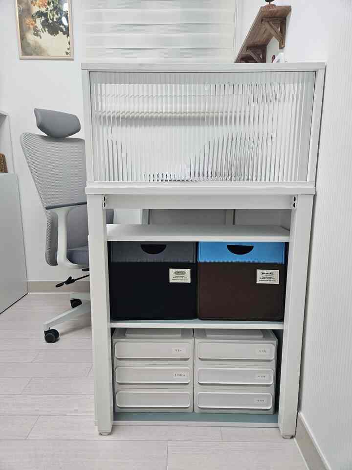 ホワイトトーンのコンパクトなホームオフィス、デスク下に整理された収納ボックスと引き出しが配置された効率的な空間