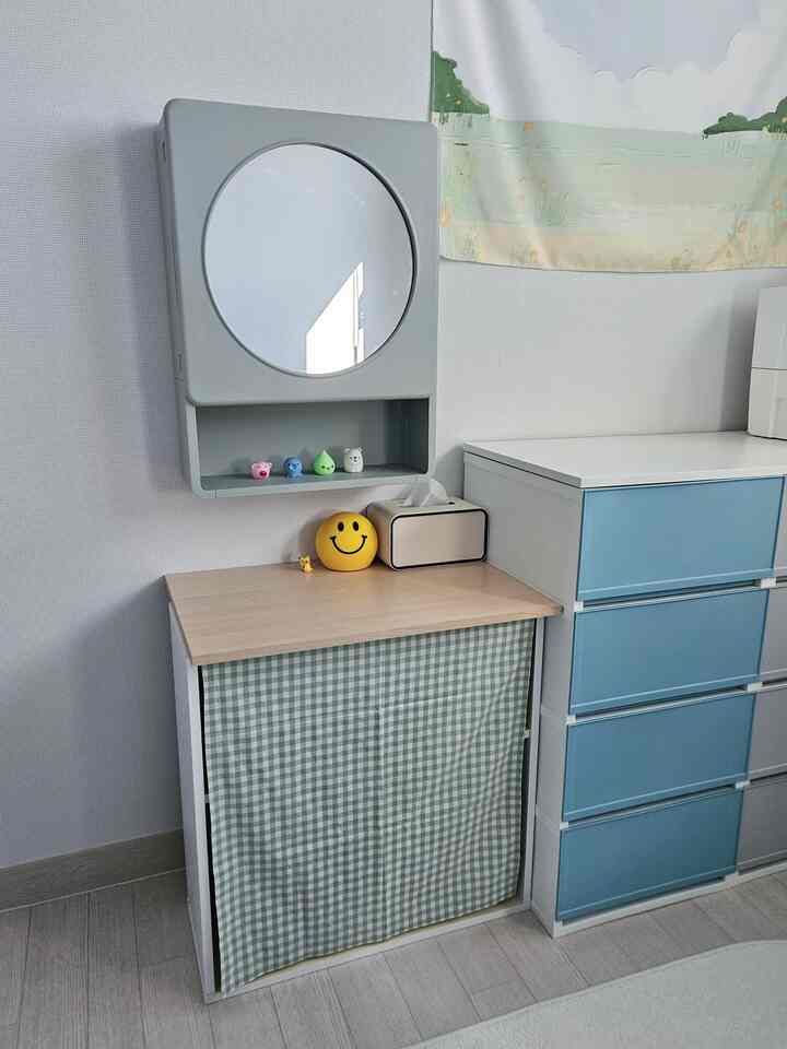 ナチュラルな色調とブルーの引き出しがある子供部屋、鏡とおもちゃが配置された落ち着いた収納空間