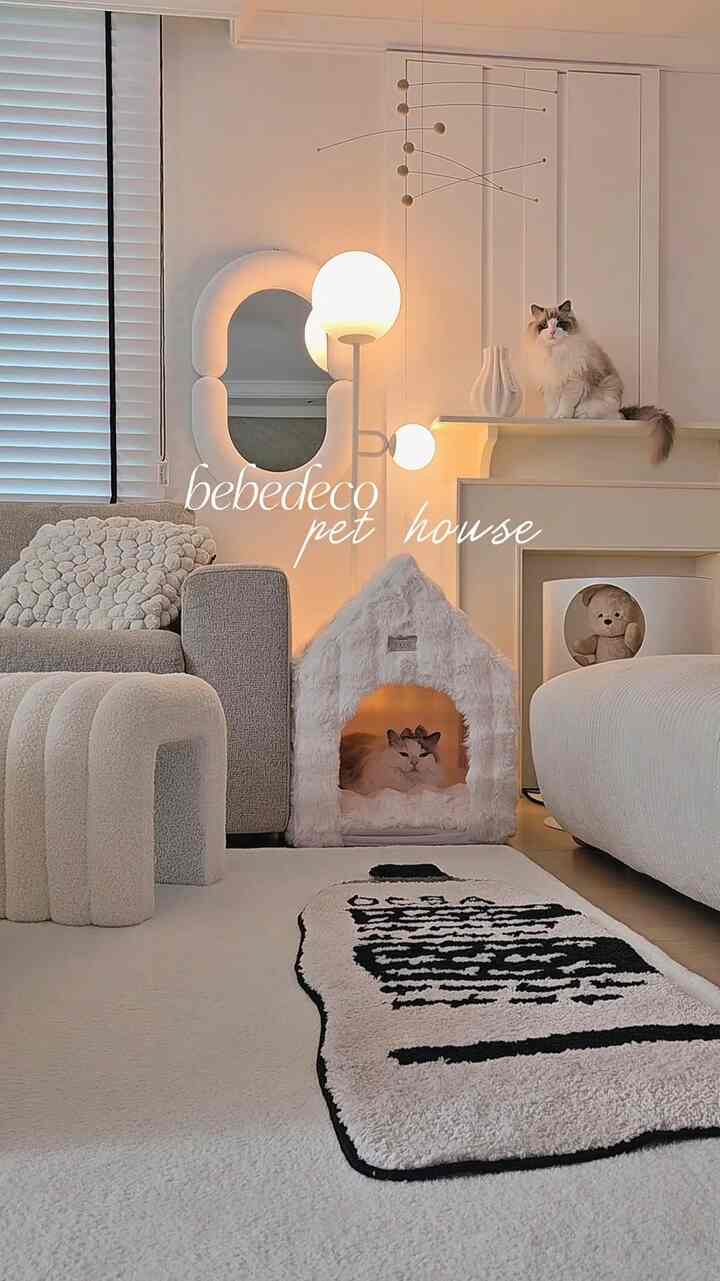 白色調のリビング、柔らかな素材のペットハウスとソファが配置され、猫がくつろぐモダンで落ち着いた雰囲気のインテリア