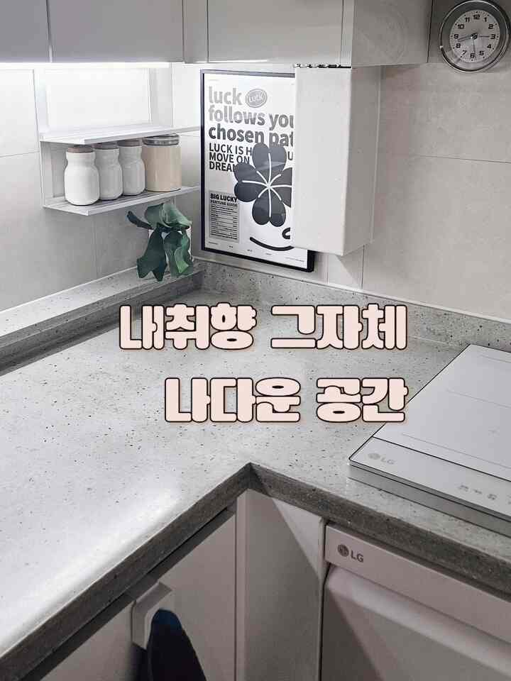 ホワイトとグレーのトーンのキッチン空間、整頓された収納とポスターが配置されたミニマルなキッチンインテリア