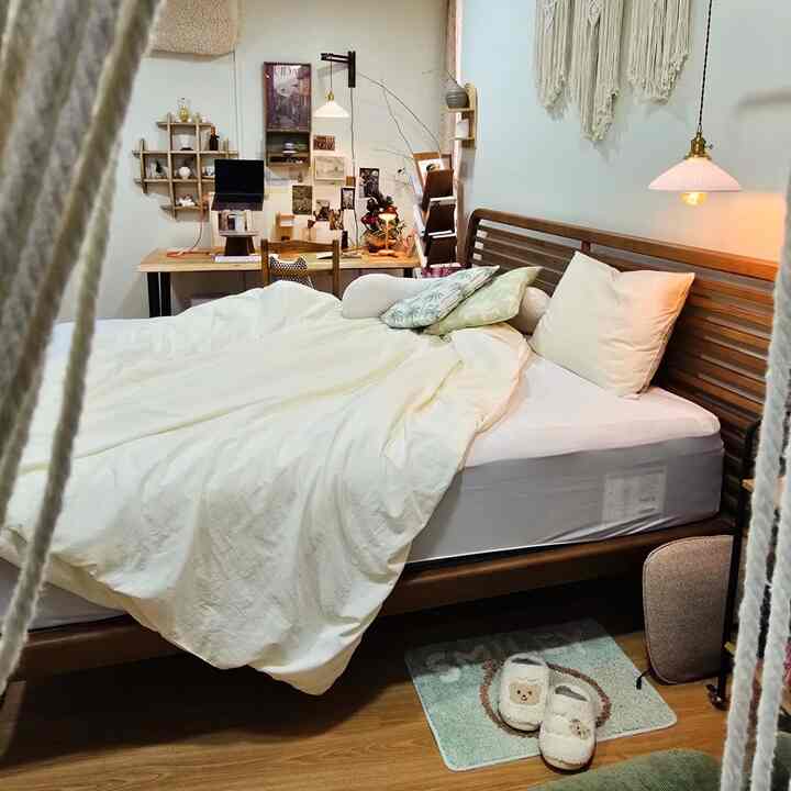 ナチュラルな色調の寝室、木製ベッドと白い寝具、ワークデスクが配置された雰囲気のあるインテリア