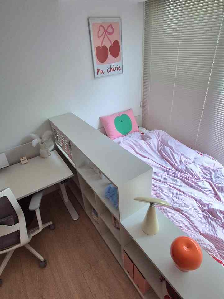 白とピンクの色調の子供部屋、ベッドと机、収納棚が配置された雰囲気のあるインテリア