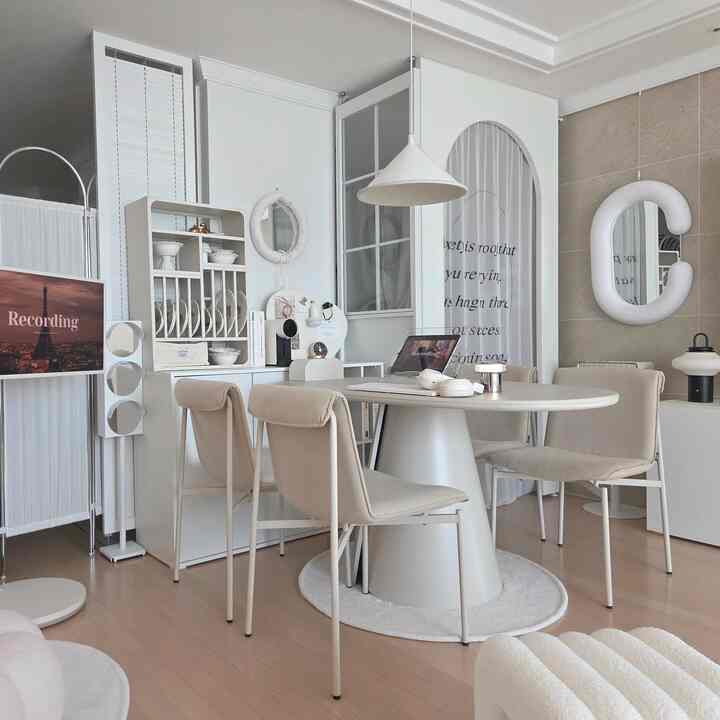 ホワイトとベージュの色調のダイニングルーム、丸テーブルとチェアが配置された清潔感のあるモダンな空間