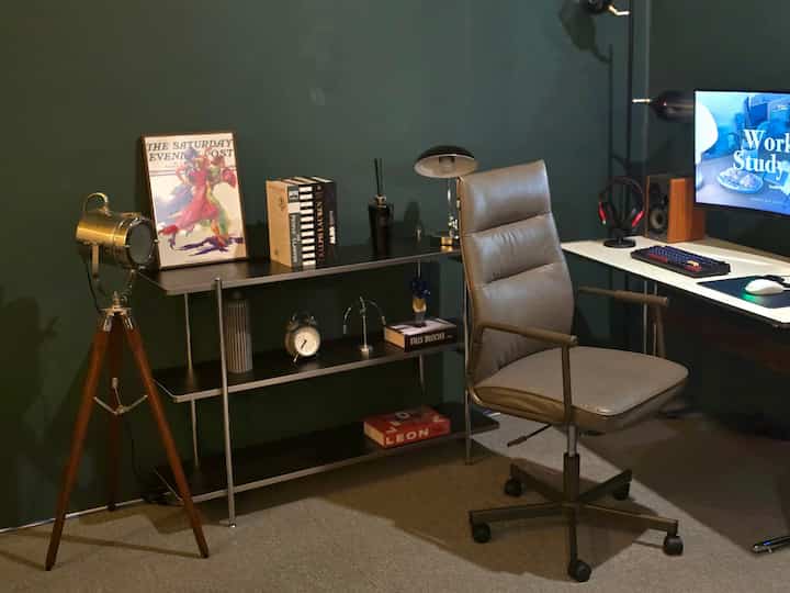 落ち着いたグレーと濃いグリーンのトーンのホームオフィス、ミッドセンチュリーモダンスタイルのオフィスチェアとデスク、ヴィンテージのフロアランプを配した雰囲気のあるインテリア