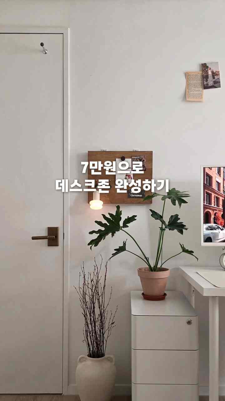 ホワイトと木目調が調和するデスクゾーン、植物と収納棚が配置された清潔感のあるナチュラルな空間